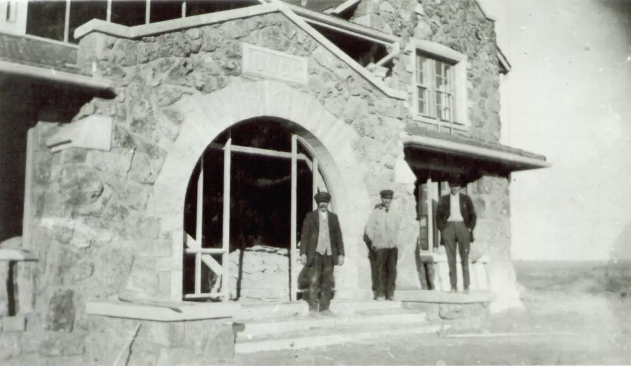 Historic photograph of The Big House at Four Sixes Ranch with ranch workers standing outside the stone ranch headquarters.